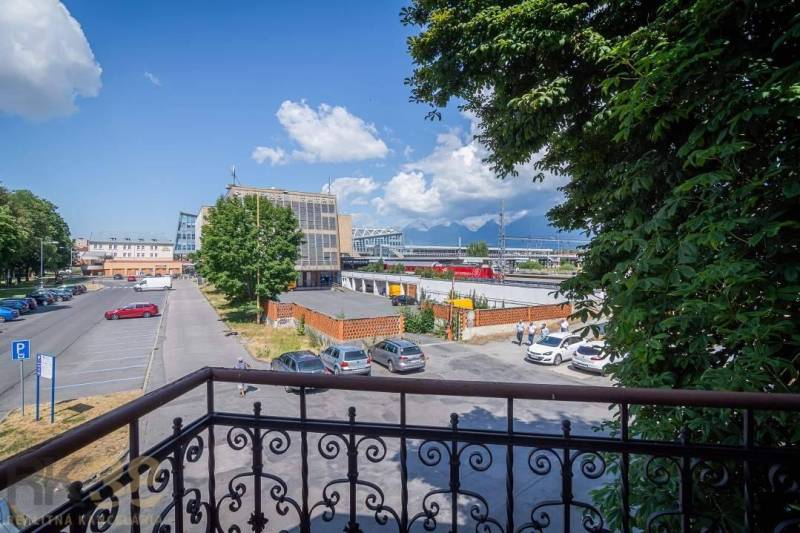 A spacious room in a building with a wood-patterned floor and windows.