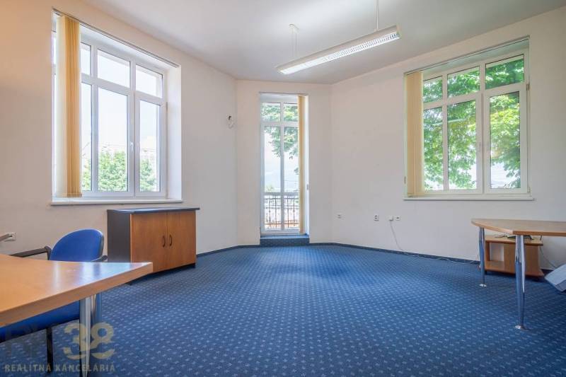 Office with shelves, desks, and computers in a building.