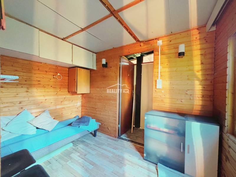 A room with a sofa, storage space, and a wooden decor floor in the Gardens.