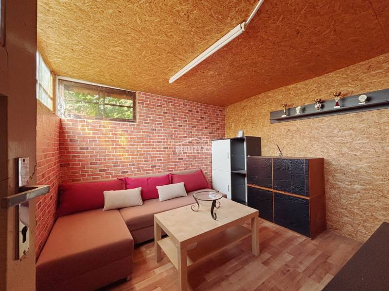 A room with a sofa, a brick wall, wooden decor, and shelves in the Gardens.