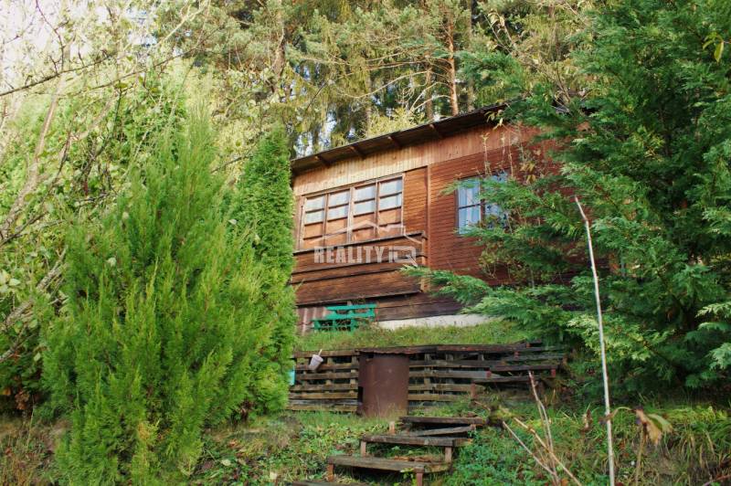 Wooden cottage surrounded by dense greenery in the Gardens on Budatínska Street in Žilina.