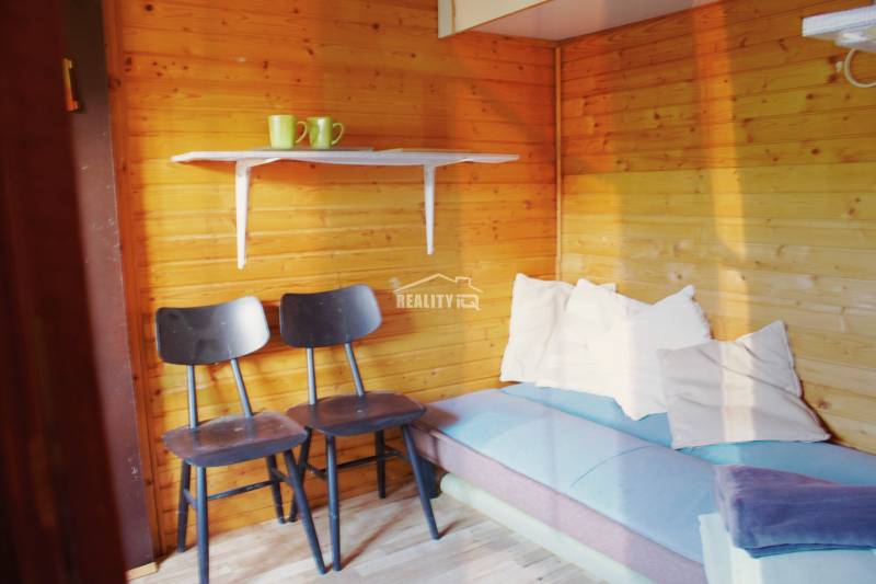 Wooden interior with chairs, a sofa, and a shelf with mugs, Gardens.