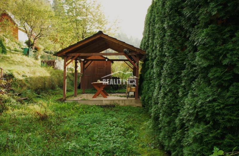 Gardens in Budatín, Žilina: A wooden shelter surrounded by lush green vegetation.