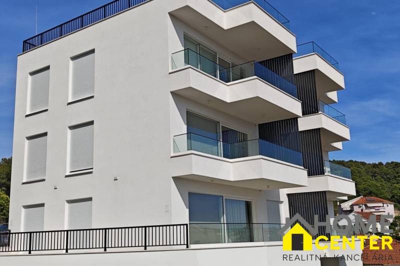 A villa in Trogir with glass balconies and a white facade against the blue sky background.