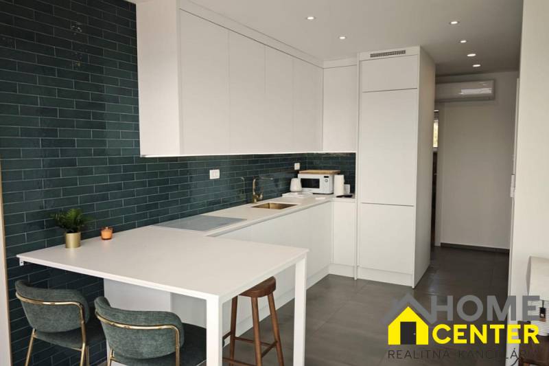 A kitchen in a villa with white cabinets and dark tiles, tiled flooring.