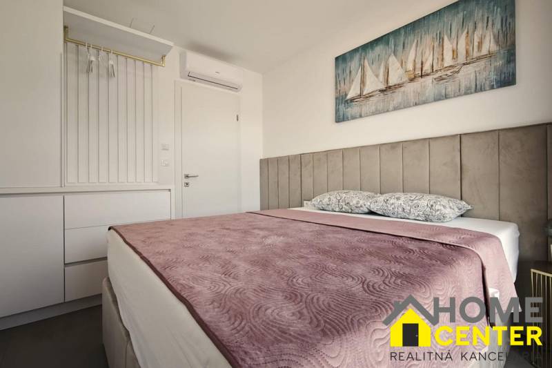 A bedroom in a villa with a bed, wardrobe, and art of sailboats on the wall.