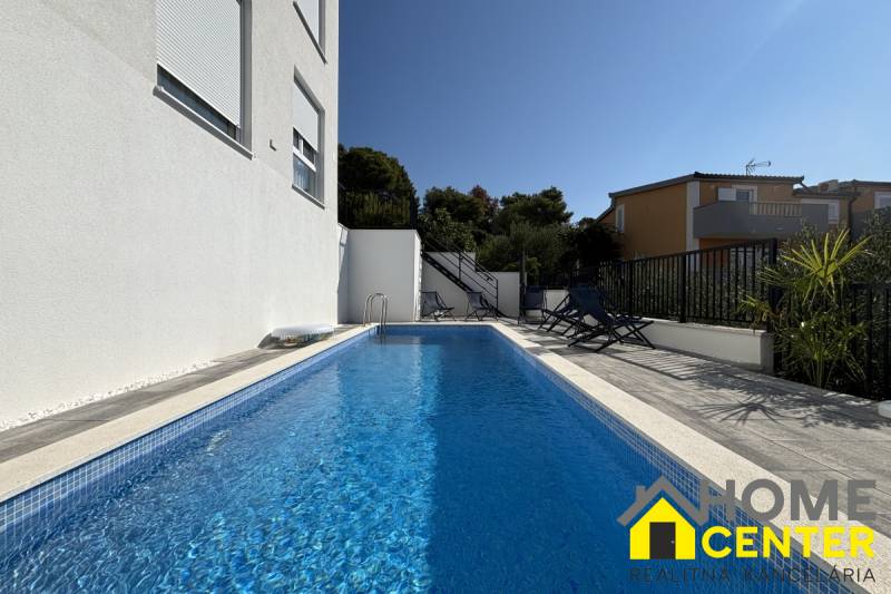 A pool in a villa in Trogir with loungers and walls in white design.