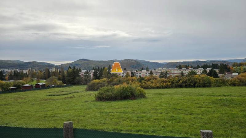Gardens on A. Hlinka Street in Zvolen, with buildings and forests in the background.