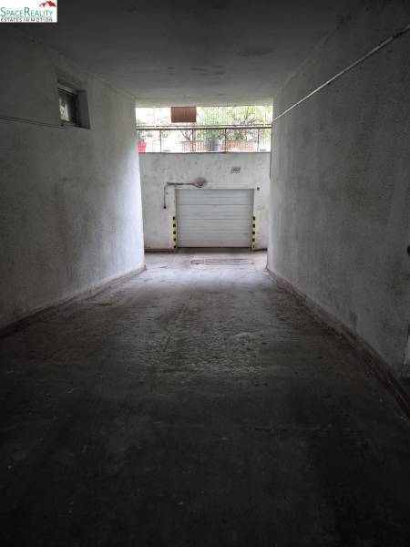 Underground garage with white walls and a rolling gate on Medená Street.
