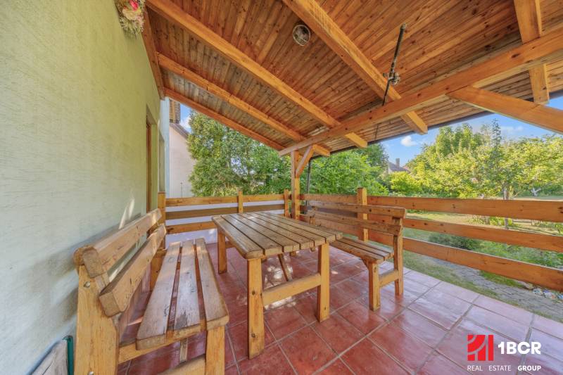 A terrace of a family house with wooden seating and a view of the garden.
