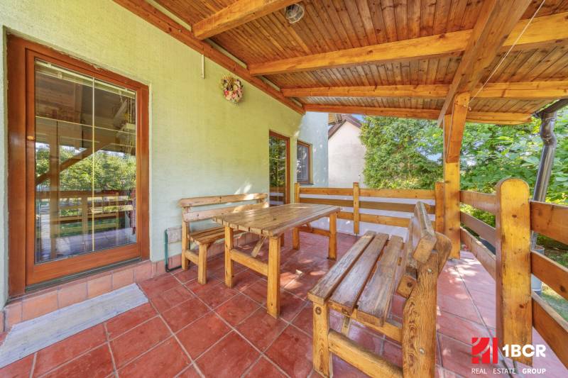 Wooden seating on the terrace of a family house with a view of the garden.