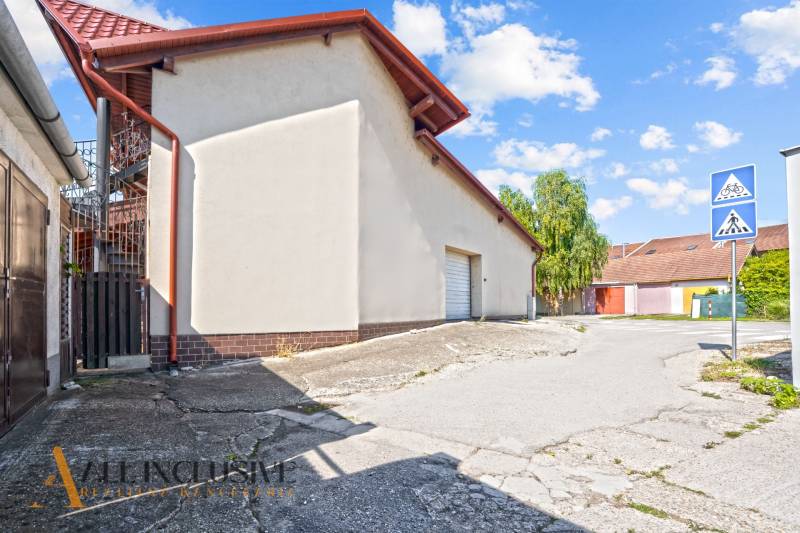 Commercial premises in Dunajská Streda with a white facade, metal roof, next to the sidewalk.