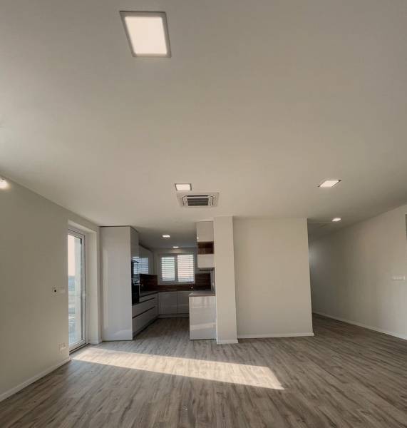 Spacious living room in a family house with a kitchen and a wooden decor floor.