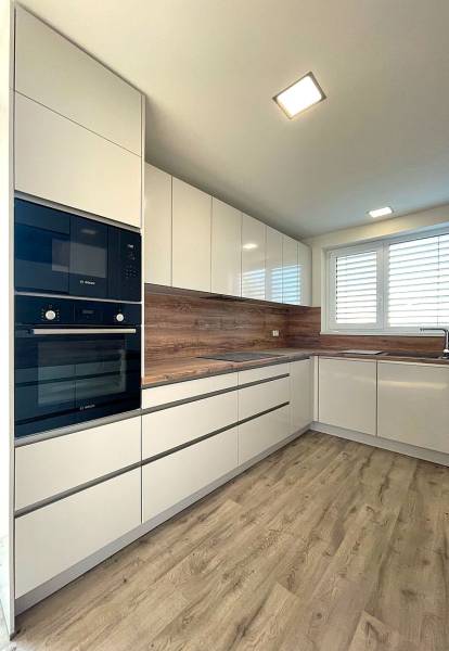 A kitchen in a family house with white cabinets and a wood-patterned floor.
