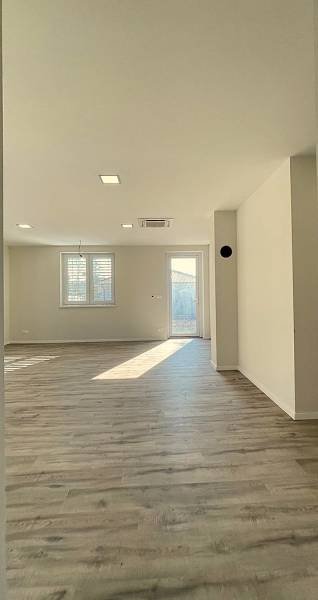 Interior with wood-patterned flooring in a family house. Lighting through two windows.