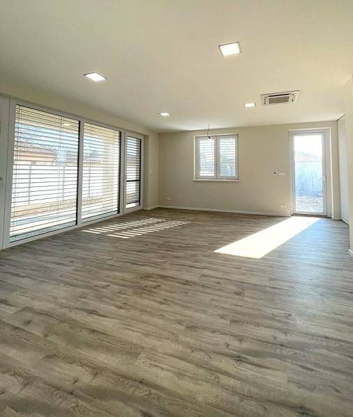 Living room in a family house with spacious windows and a wooden decor floor.