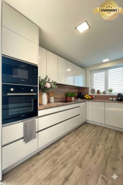 A kitchen in a family house with white cabinets and a wood-patterned floor.