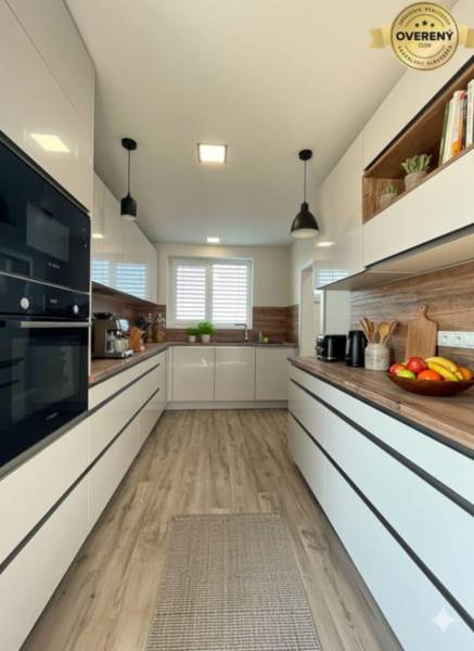 Modern kitchen in a family house with white cabinets and a wood-patterned floor.