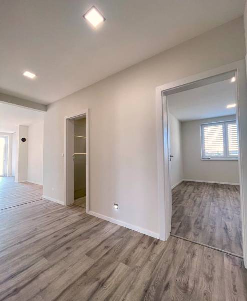 A hallway in a family house with a wooden decor floor and light-colored walls.