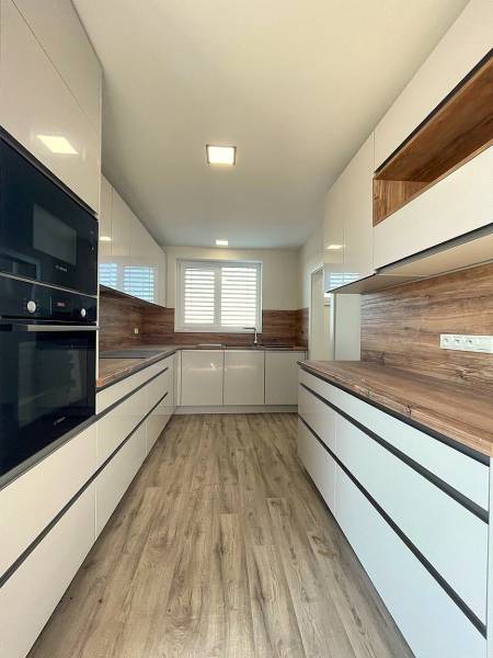 A kitchen in a family house with a wooden decor floor and white cabinets.