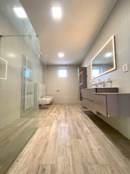 A bathroom in a family house with a wooden decor floor and a shower.