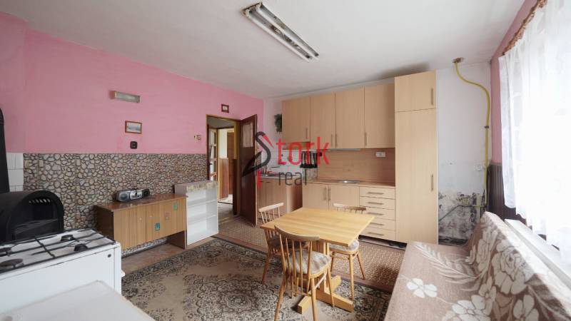 A kitchen in a family house with pink walls and simple wooden furniture.