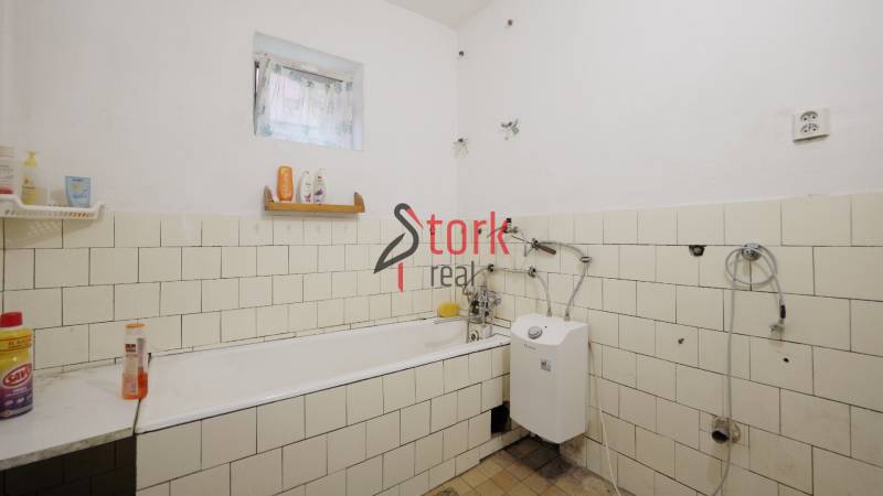 Bathroom in a family house with a bathtub and a gas boiler, tiled with white tiles.