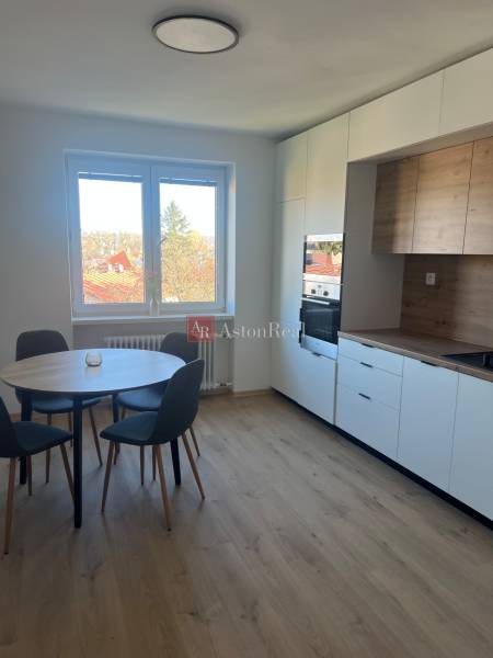 Dining nook with a round table and kitchen unit, floor with wooden decor.