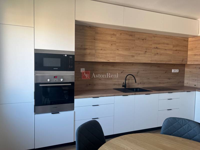 A kitchen with white cabinets and a wood-patterned floor in a studio apartment.