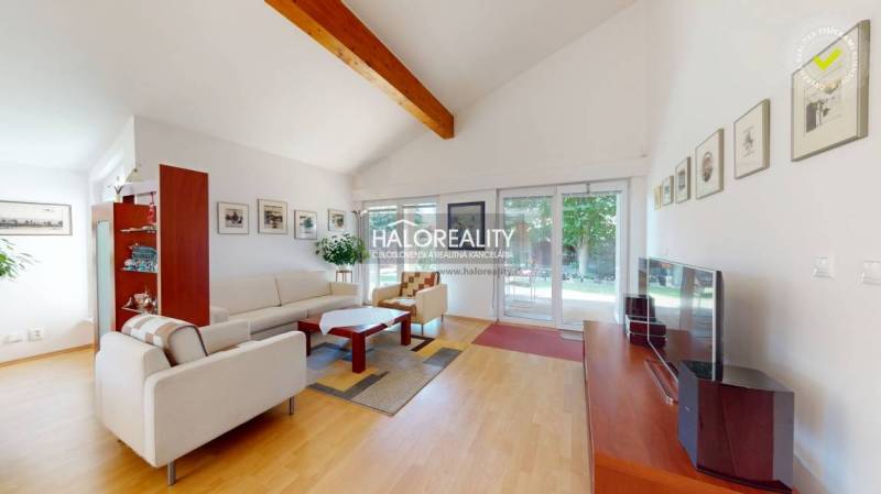 Living room in a family house with comfortable seating, wooden decor, and large windows.