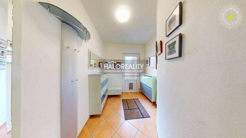 A hallway in a family house with tiles, furniture, and paintings on the walls.