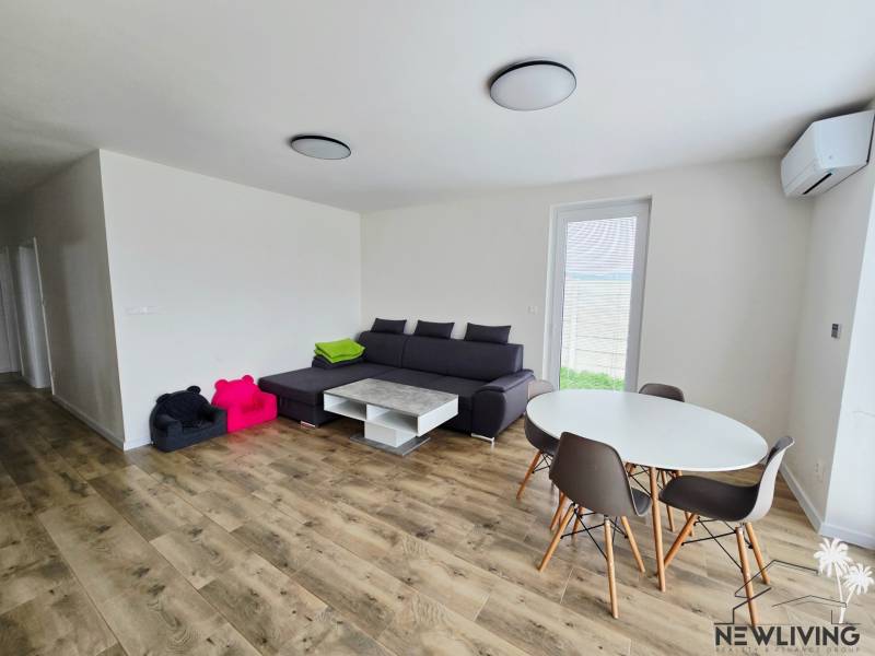Living room of a family house with a wooden decor floor, gray sofa, and round table.