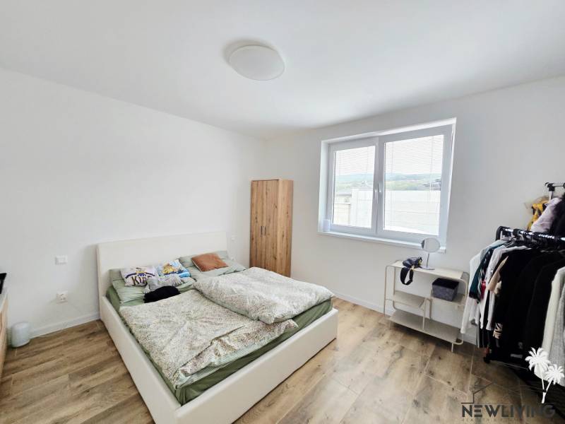 Bedroom with a bed, wardrobe, and wood-decorated floor in a family house.