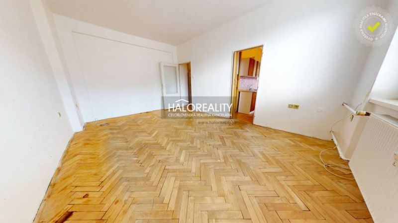 Living room in a two-room apartment with a wooden decor floor and a large window.