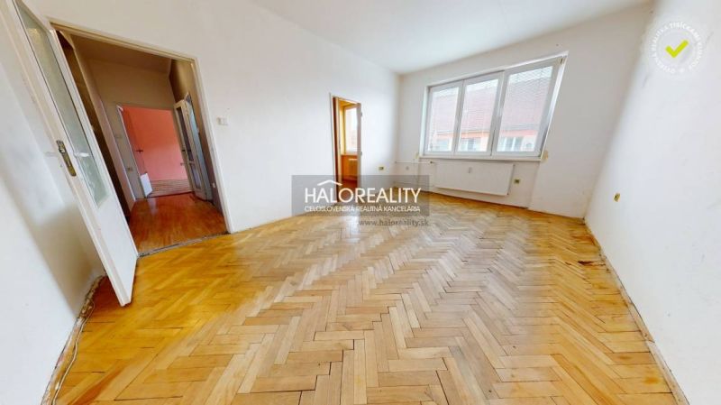 A room in a 2-room apartment with a wood-patterned floor and a large window.