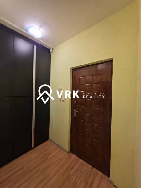Entrance hall in a studio apartment with wood-patterned flooring and a dark wardrobe.