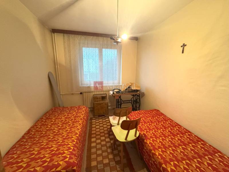 Izba v rodinnom dome s dvomi posteľami, šijacím strojom a krížom na stene.