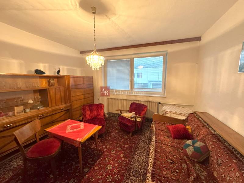 Obývacia izba v rodinnom dome s červenými kreslami, lustrom a dreveným nábytkom.