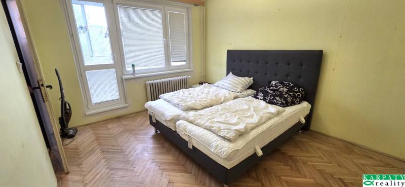 A bedroom with a large bed and a wooden decor floor in a 3-room apartment.