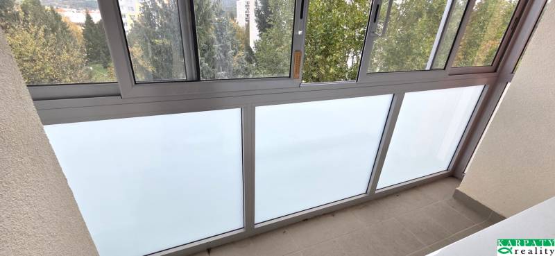 A glazed loggia in a 3-room apartment with a view of greenery.