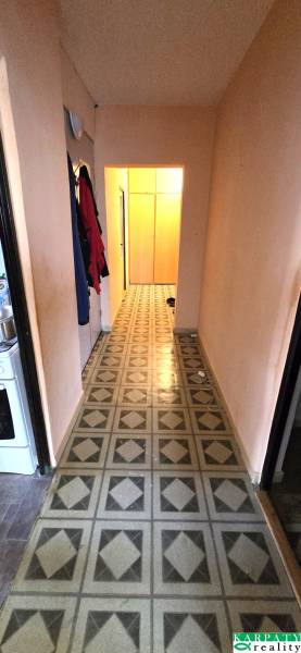 A narrow corridor in a 3-room apartment with colorful patterned linoleum.