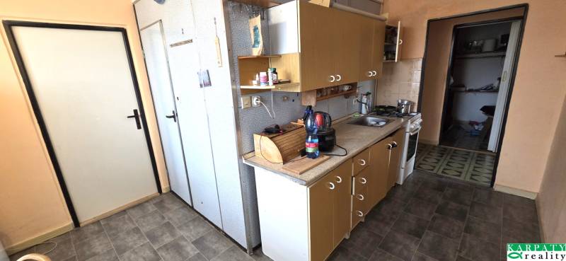 A kitchen in a 3-room apartment with a countertop and doors, floor with wood decor.