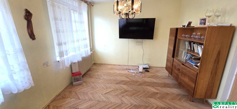 Living room with a TV, display cabinet, and wooden decor flooring in a 3-room apartment.