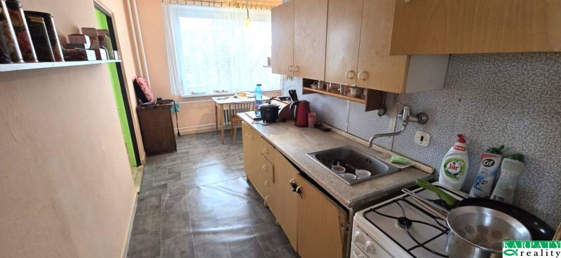 A kitchen in a 3-room apartment with a simple kitchenette, seating, and shelves.