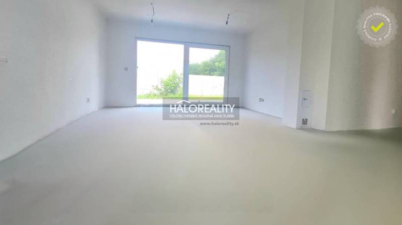 A spacious room with a large window in a family house, white walls, view of the garden.