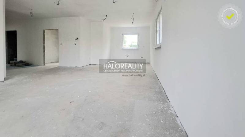 A spacious unfurnished room in a family house with white walls and a window.