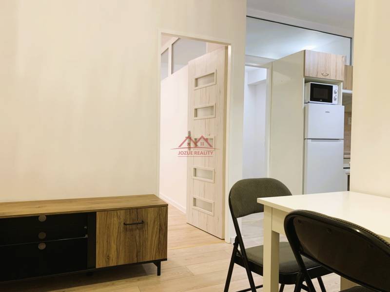 Interior of a 3-room apartment with a dining table, folding chair, and wooden decor of a sideboard.