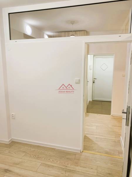 Interior of a 3-room apartment with wood-patterned flooring and white walls.