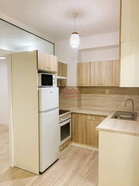 A kitchen in a 3-room apartment with a wooden decor floor and wooden cabinets.