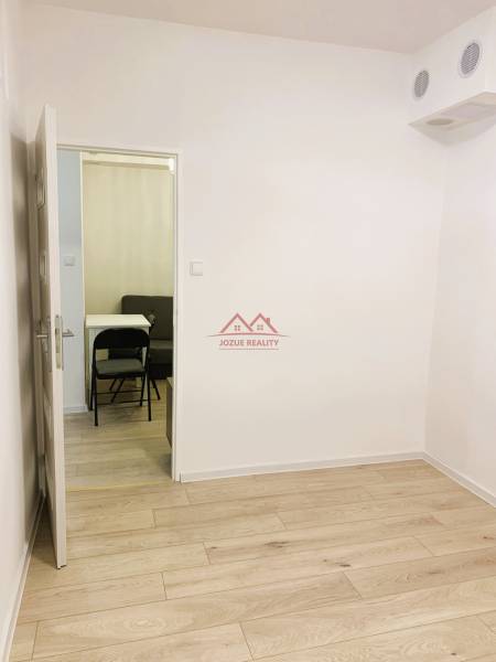 A room with a wooden decor floor in a 3-room apartment, entrance to another room.